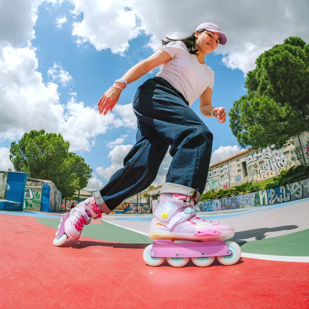 A skater in pink and white Flying Eagle skates on a colorful outdoor court.
