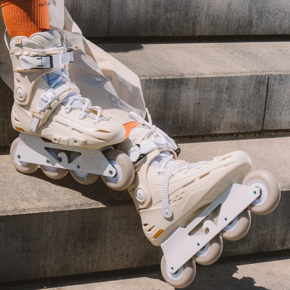 White Flying Eagle inline skates with orange socks resting on concrete steps.